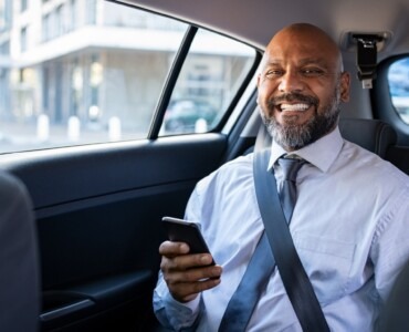 Homme d'affaires souriant à l'arrière d'un VTC électrique Crénolia à Paris