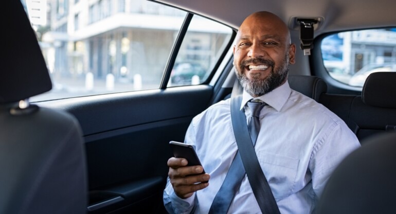 Homme d'affaires souriant à l'arrière d'un VTC électrique Crénolia à Paris