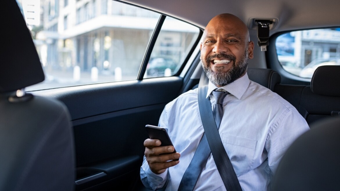 Smiling businessman in the back seat of a Crénolia electric private car in Paris